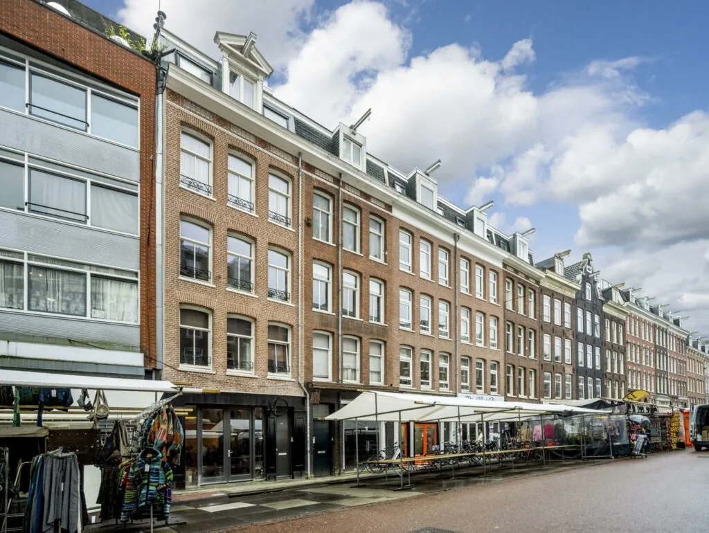 Straatbeeld van de Albert Cuypstraat in Amsterdam met marktkramen en karakteristieke gevels.